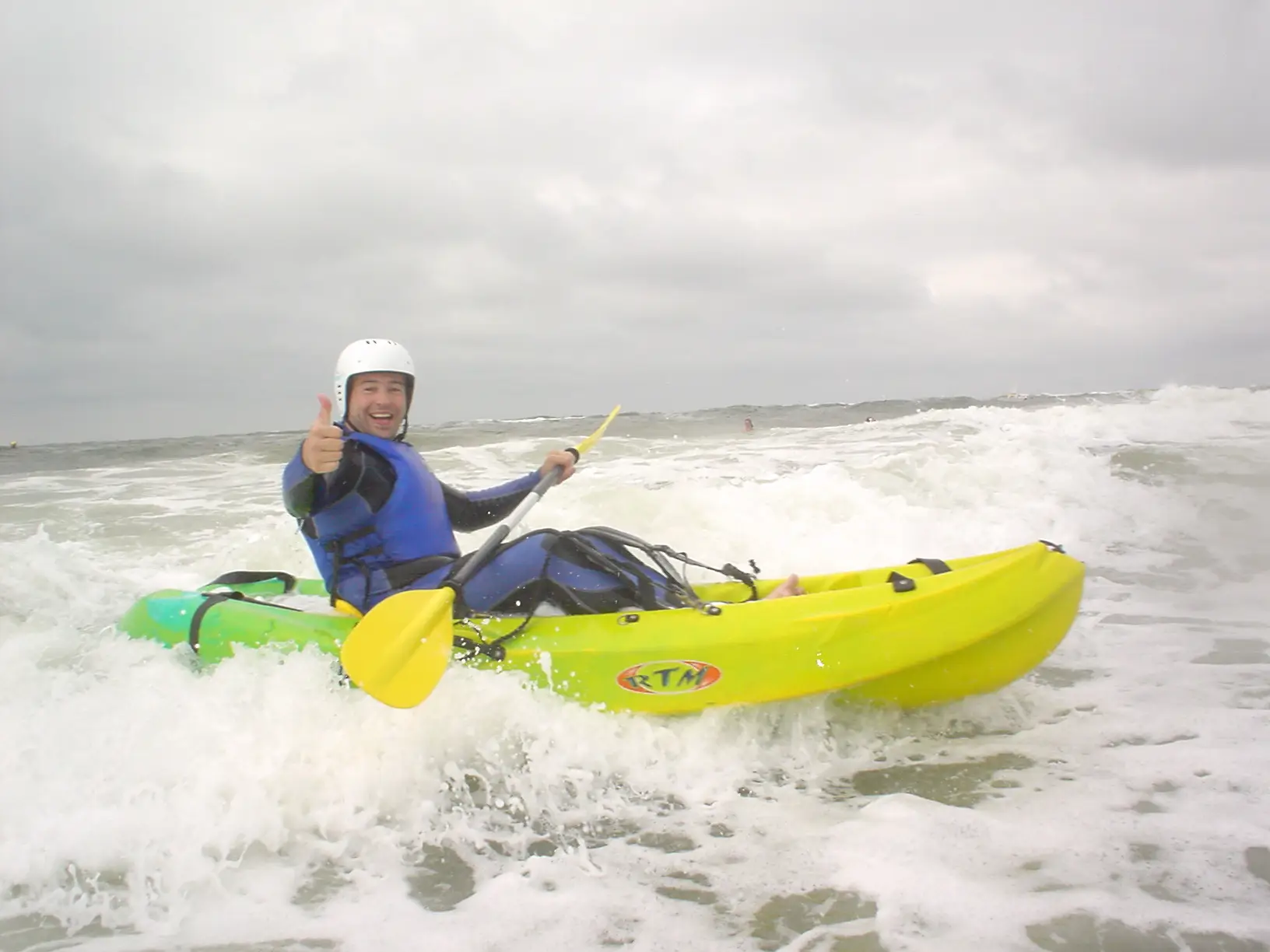 Brandingkajakken in een gele kajak op de golven van de Noordzee.