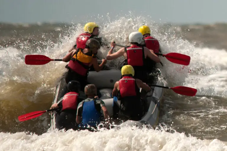 Groep collega's die door de branding proberen te komen tijdens het raften als onderdeel van een teambuilding evenement bij Outstanding