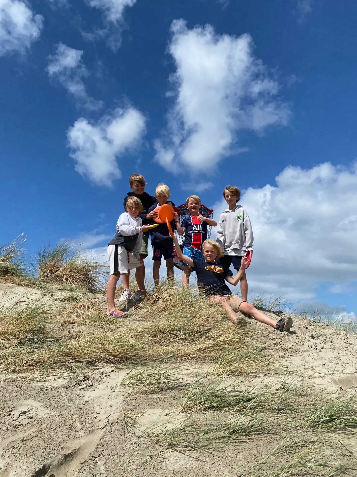een groep kinderen tijdens een ronde discgolfen in de duinen
