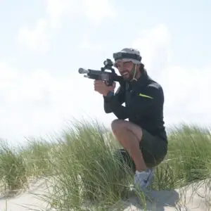 Deelnemer mikt op tegenspeler tijdens lasergame in de duinen