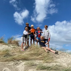 een groep kinderen tijdens een ronde discgolfen in de duinen