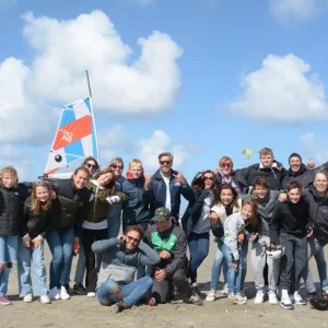 Schoolgroep geniet van een spannende blokart ervaring op het strand bij Outstanding, waarbij ze samenwerken en plezier hebben tijdens deze mooie beleving.